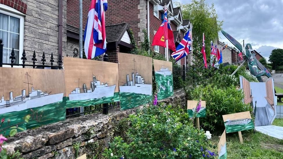 Paintings of warships hung against a house as a D-Day memorial