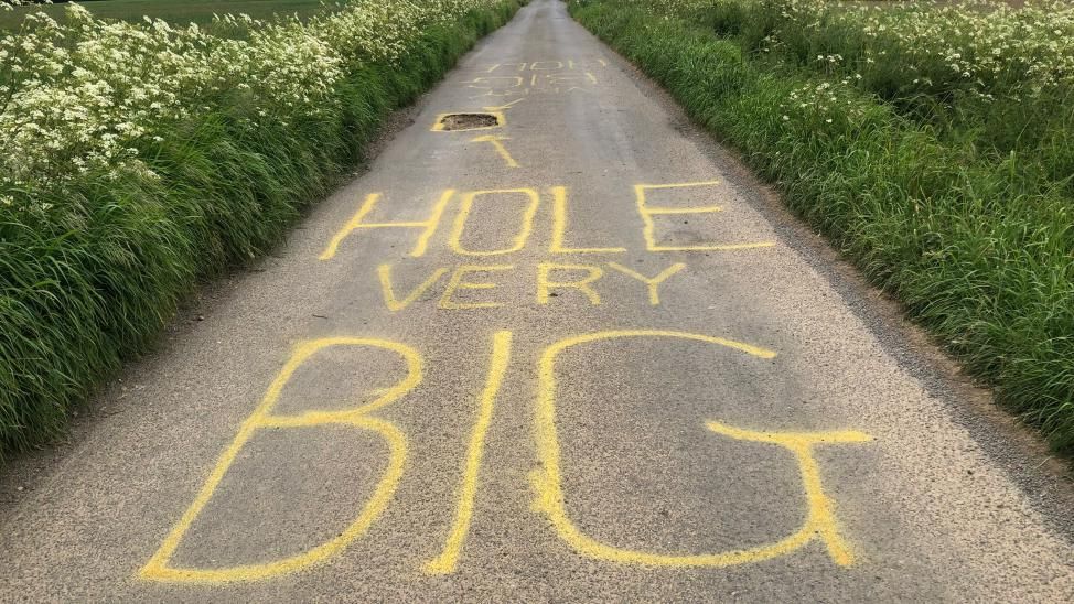 "Hole very big" painted on a road