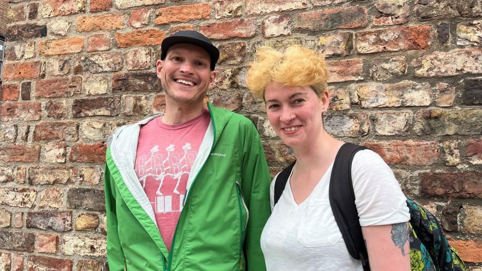 University researchers Dr Tyson Mitman and Maisie Wilson stood in front of a brick wall