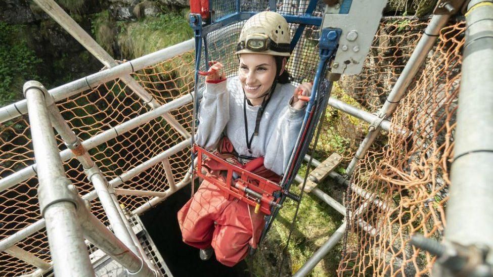 A woman using the winch into the cave