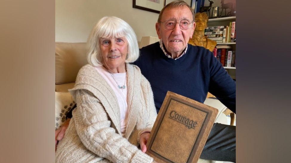 Rosemary and Alfred Anslow with a book that their son Adrian bought.