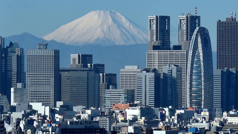 Japan's highest mountain, Mount Fuji (C) is seen behind the skyline of the Shinjuku area of Tokyo on December 6, 2014.