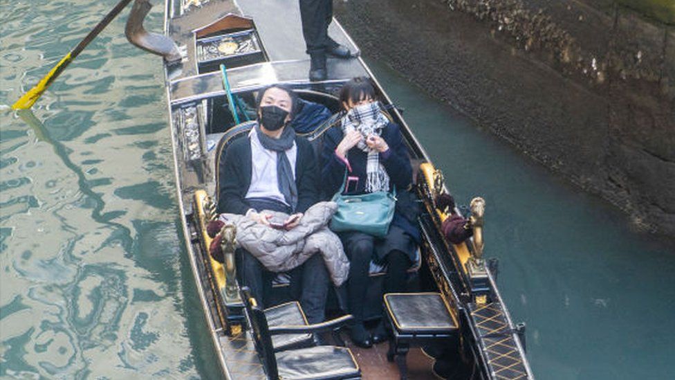 Tourists wear protective facemasks as they visit Venice after the cancellation of the Venice Carnival festivities on February 24, 2020 in Venice, Italy. The final days of the carnival were cancelled due to the outbreak of the coronavirus COVID-19 in Italy, which has killed six people in the country.