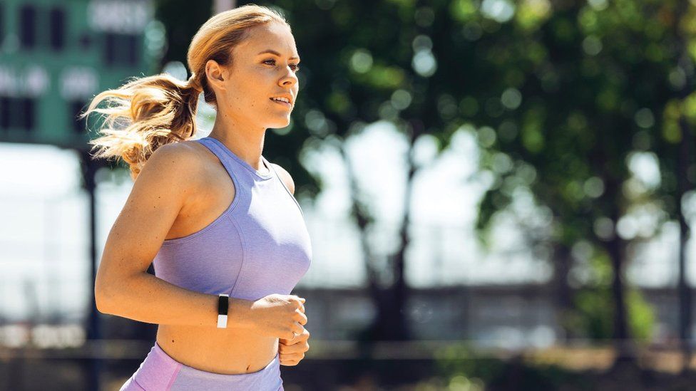 Woman running while wearing a Fitbit device