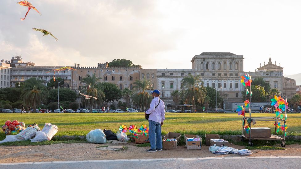 A Bangladeshi trader sells kites in Foro Italico, Palermo, Sicily - November 2021