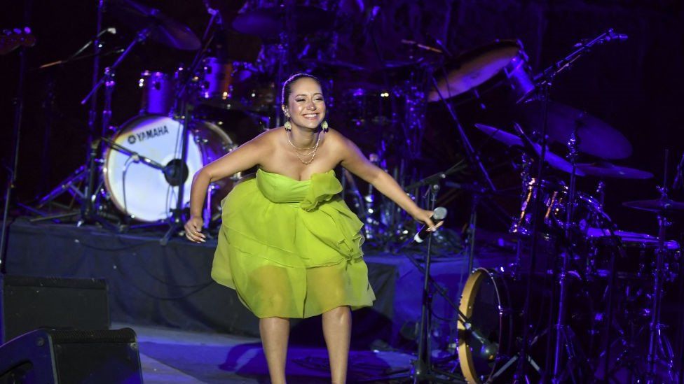 Tunisian singer Noor Arjourn singing in a green dress on stage. There are drums behind her in Carthage, Tunisia - Wednesday 27 July 2022