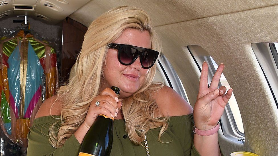 Gemma Collins holds a bottle of champagne in a private jet