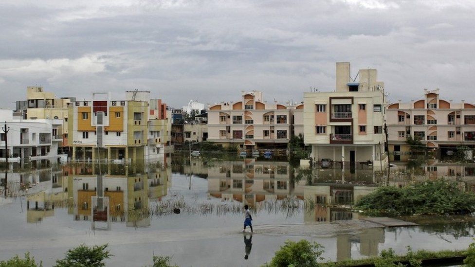 A man walks through a flooded residential area in Chennai, India, December 2, 2015