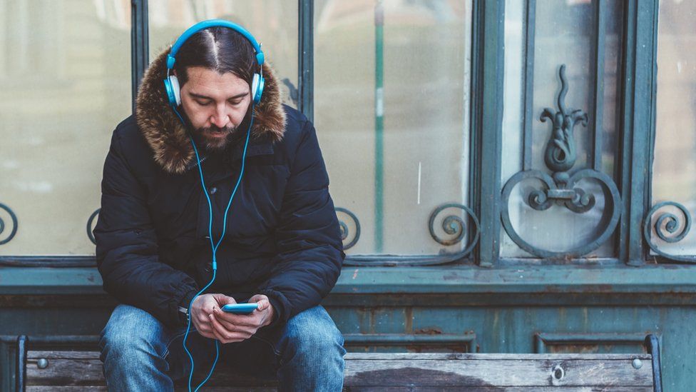 Стоковое изображение человека, слушающего музыку на своем телефоне