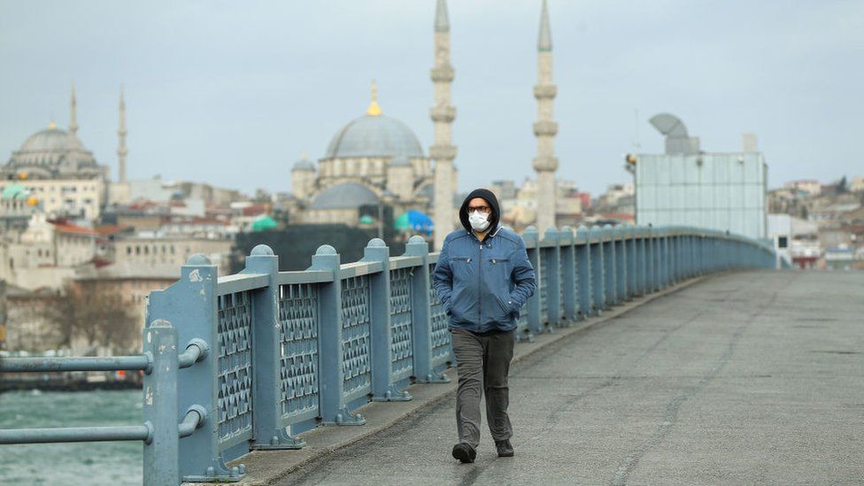 A solitary man walks wearing a face mask