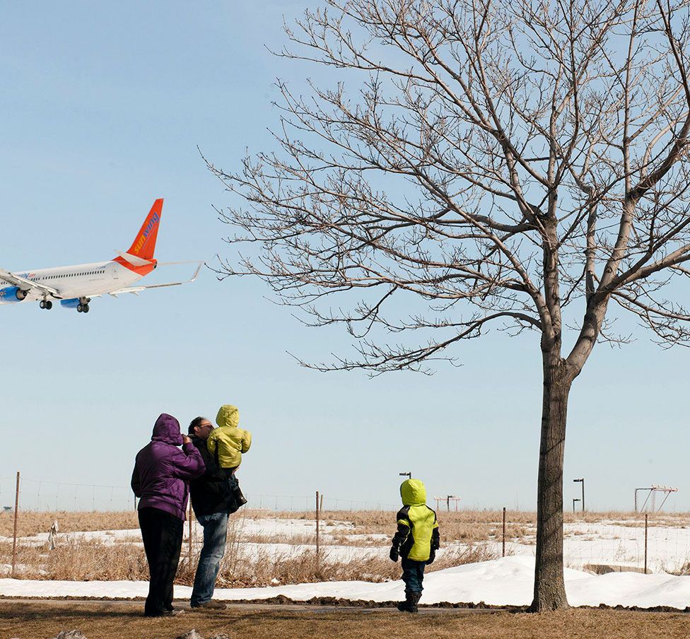 A family watch a plane land at an airport