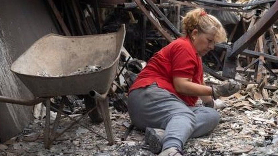 A woman lies among the remains of her burned house, following the spread of wildfires in Vina del Mar, Chile, February 4, 2024.