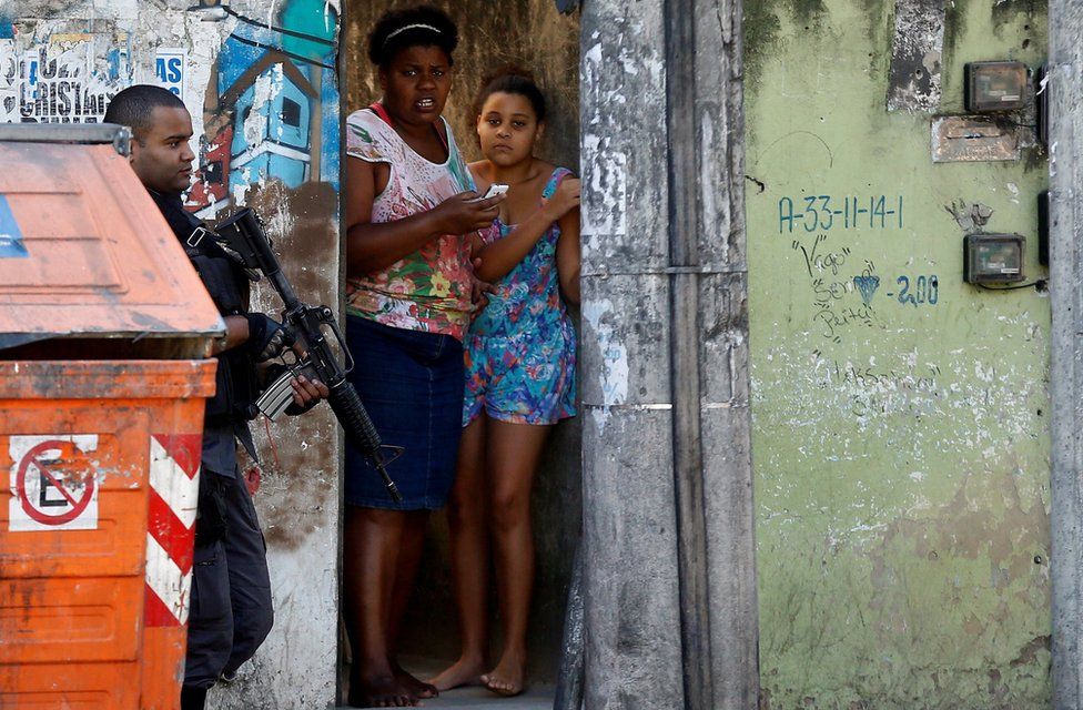 A policeman takes position during an operation against drug dealers in Cidade de Deus or City of God slum in Rio de Janeiro