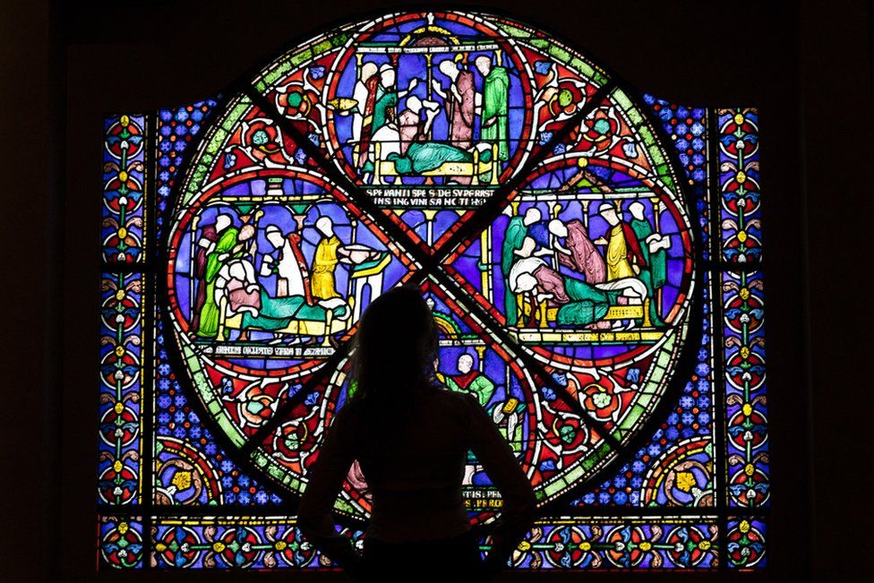 A member of staff looks at an 800-year-old stained glass window on loan from Canterbury Cathedral for a new exhibition about Thomas Becket at London's British Museum.