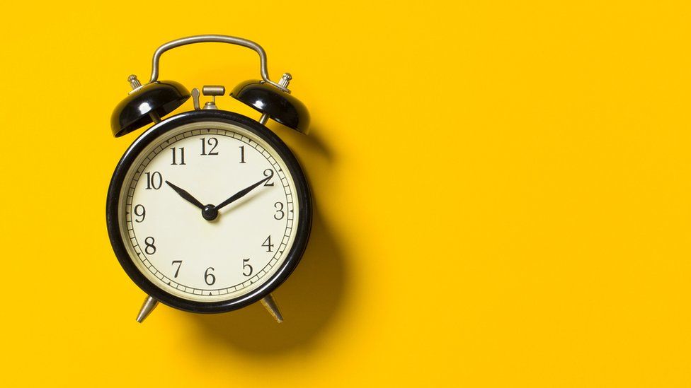 An alarm clock pictured on a yellow background
