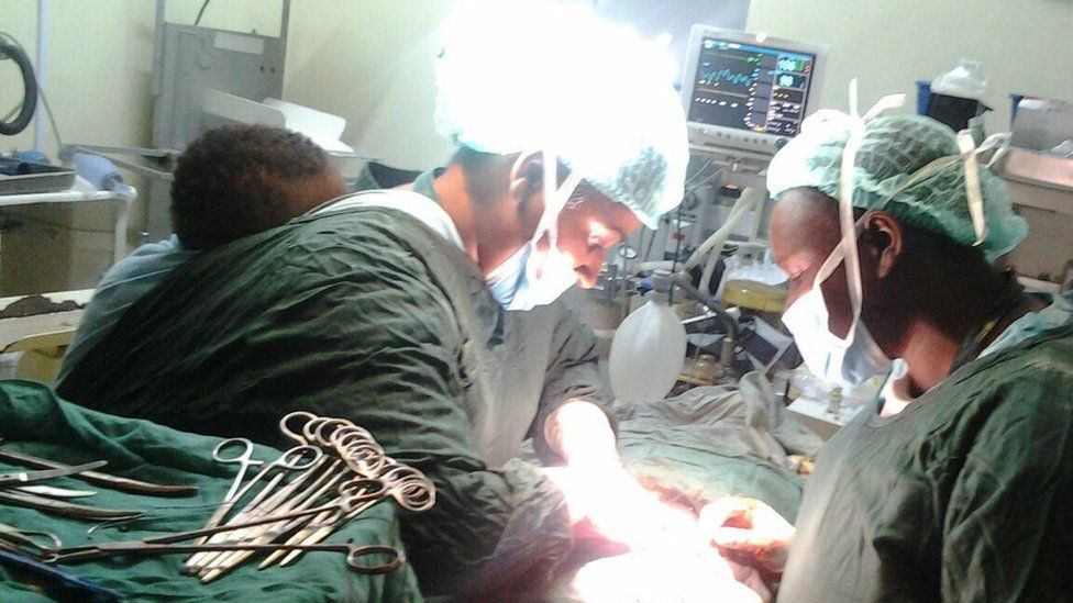 Surgeons attend to a patient in an operating theatre