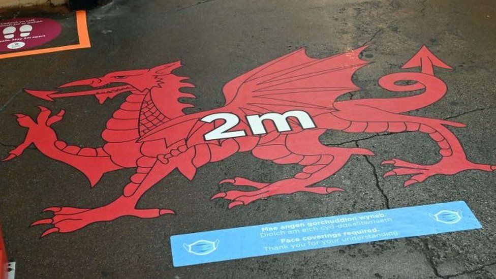 A social distancing sign showing a Welsh dragon painted on a pavement in Wrexham