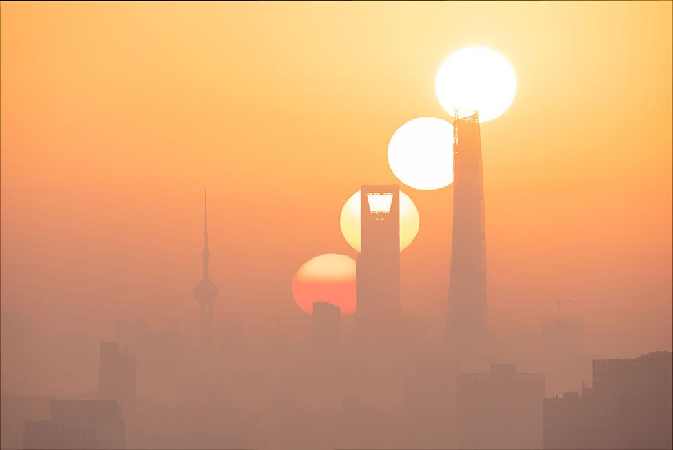 An image of the sun at different stages of a sunrise over Shanghai