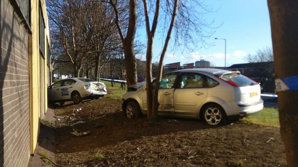 Car in wall and car against tree