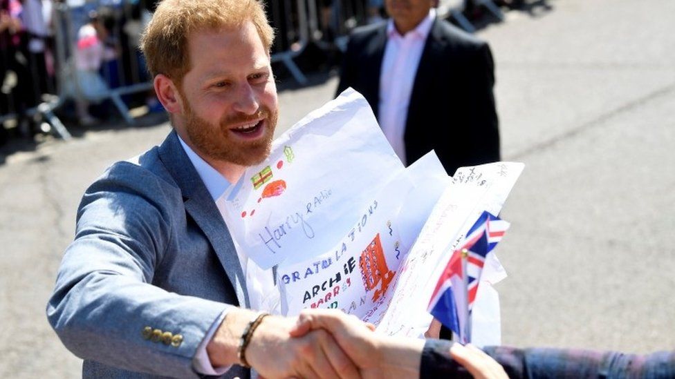 Prince Harry holds cards he received from well-wishers outside of the Barton Neighbourhood Centre