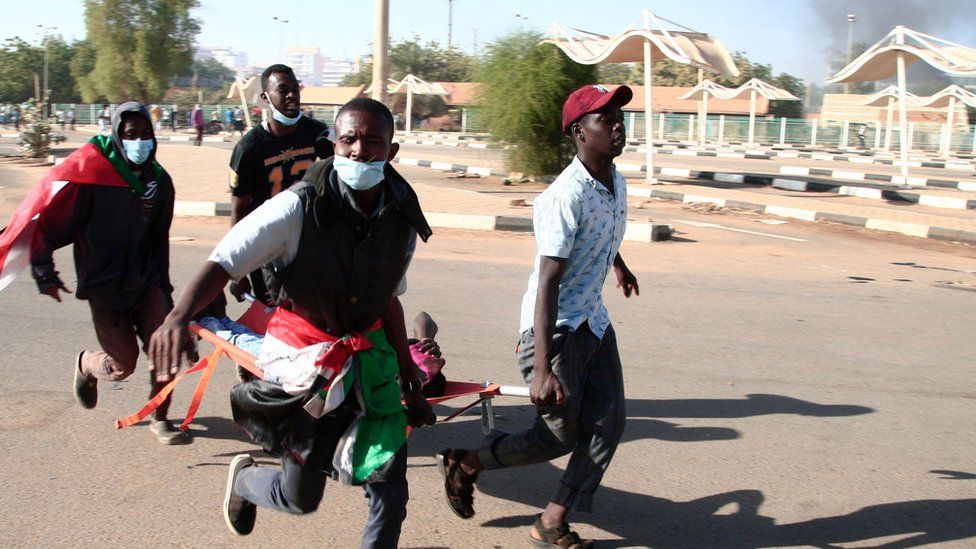 Four men carry an injured protester on a stretcher