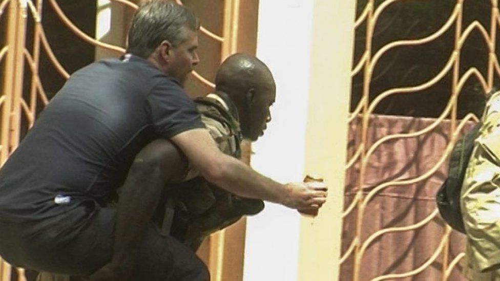 An injured rescued hostage is carried from the Radisson Hotel by security forces