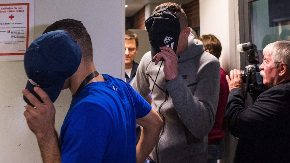Two of six young men accused of setting fire to a sleeping homeless man hide their faces as they arrive for their trial at court in Berlin, 13 June 2017