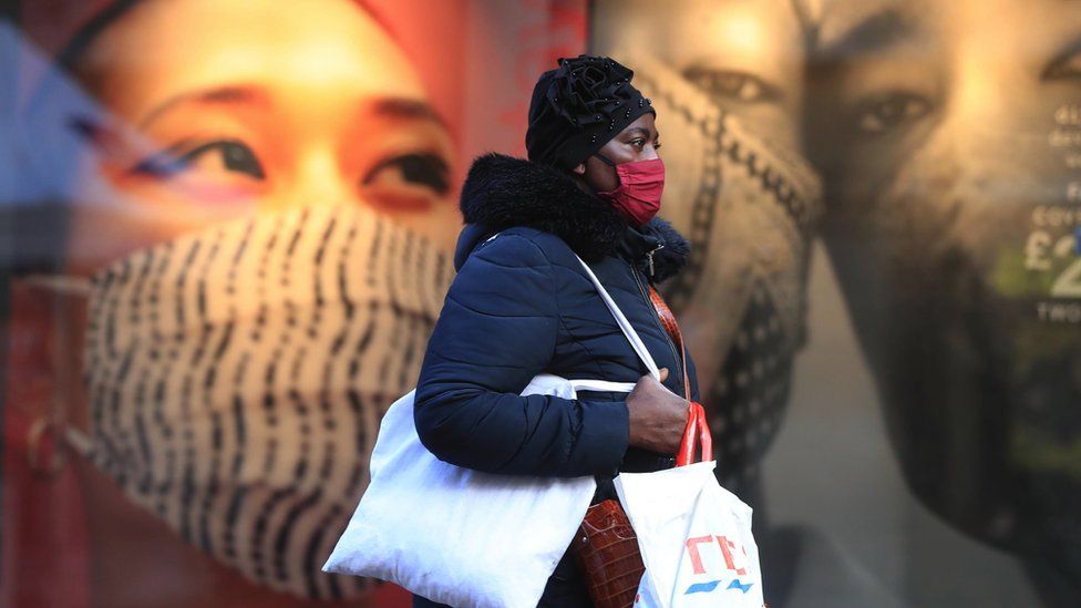 Woman wearing a face covering walking along a street, in 2020