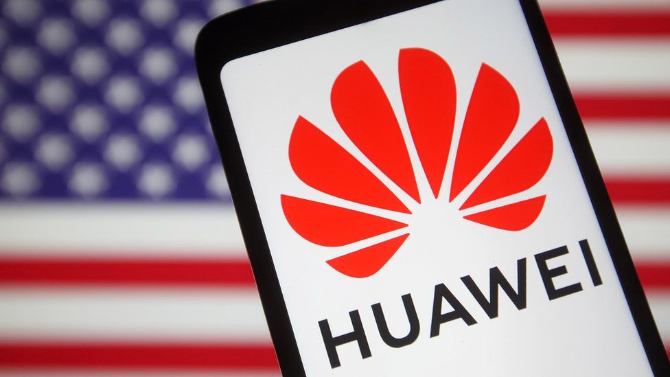 The Huawei logo on a smartphone in front of a blurred US flag