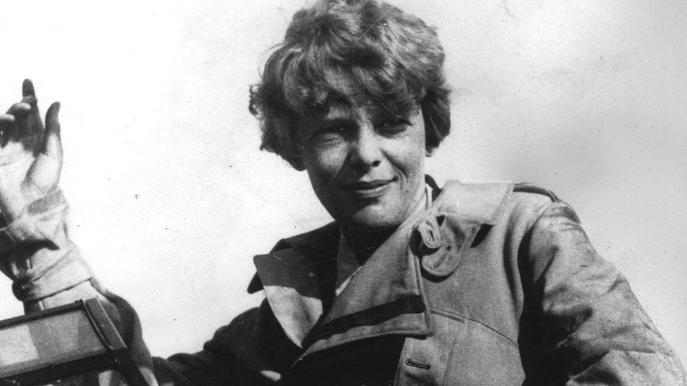 Amelia Earhart waving from the cockpit of her plane