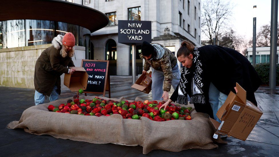 Members of the domestic violence charity "Refuge" dump rotten apples outside New Scotland Yard during a protest in London