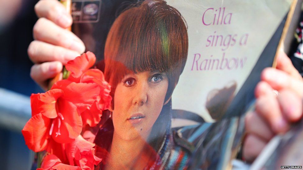 A fan holds a Cilla album on the funeral route