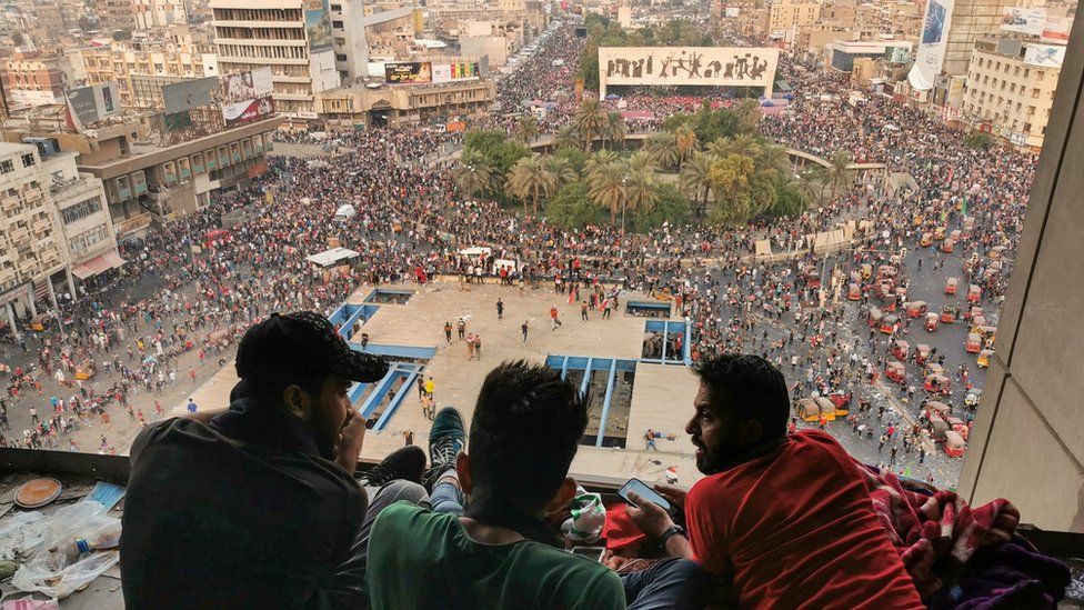 Protesters sit on top of a building near Tahrir Square in central Baghdad (28 October 2019)