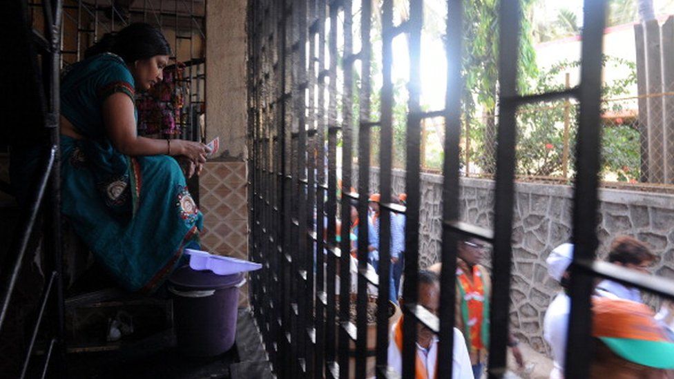 Индийская домохозяйка читает избирательную брошюру, распространенную сторонниками партии Бхаратия Джаната (BJP) возле ее дома во время предвыборного митинга в Мумбаи 10 апреля 2014 г.