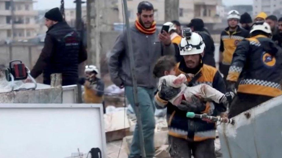 A rescue worker holds a young child
