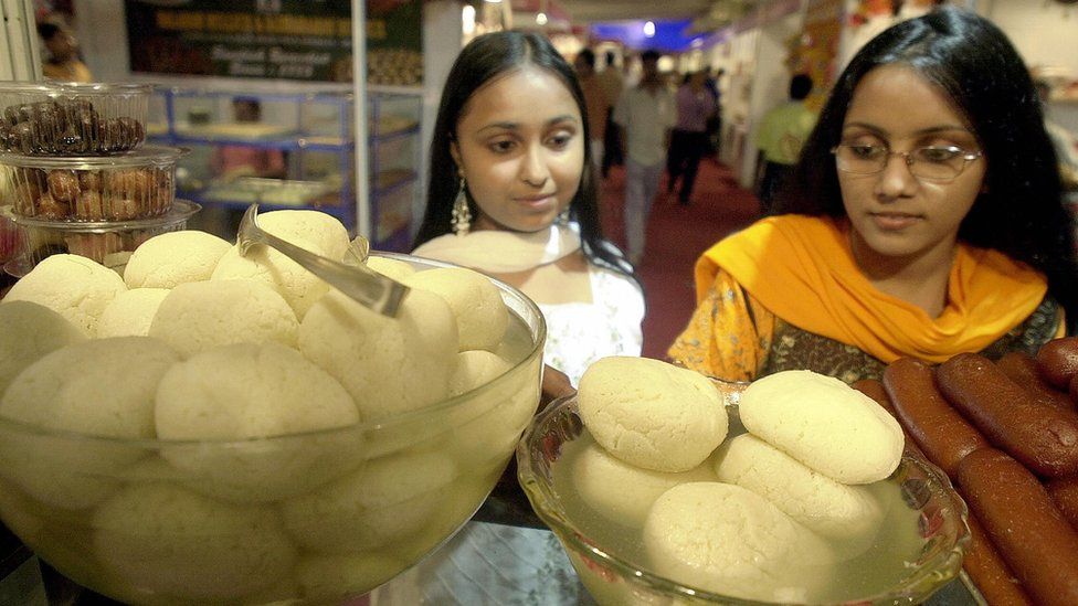 Two Indian women look at rasagollas on display in Calcutta