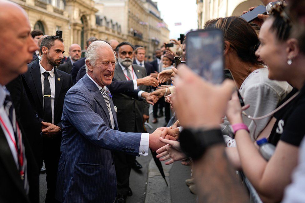 King Charles greets people during a walk from the Elysee Palace to the residence of the British ambassador to France
