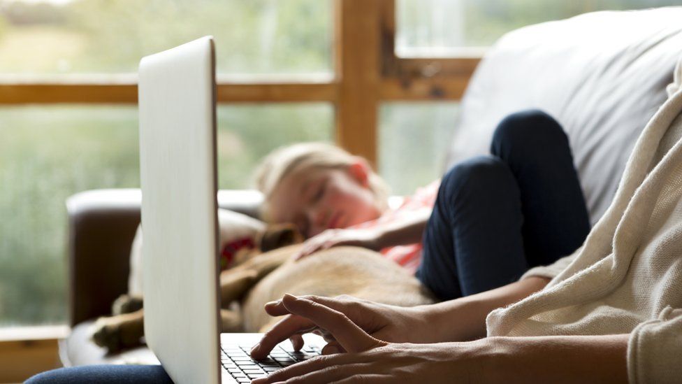Child sleeping while her mum is on her laptop