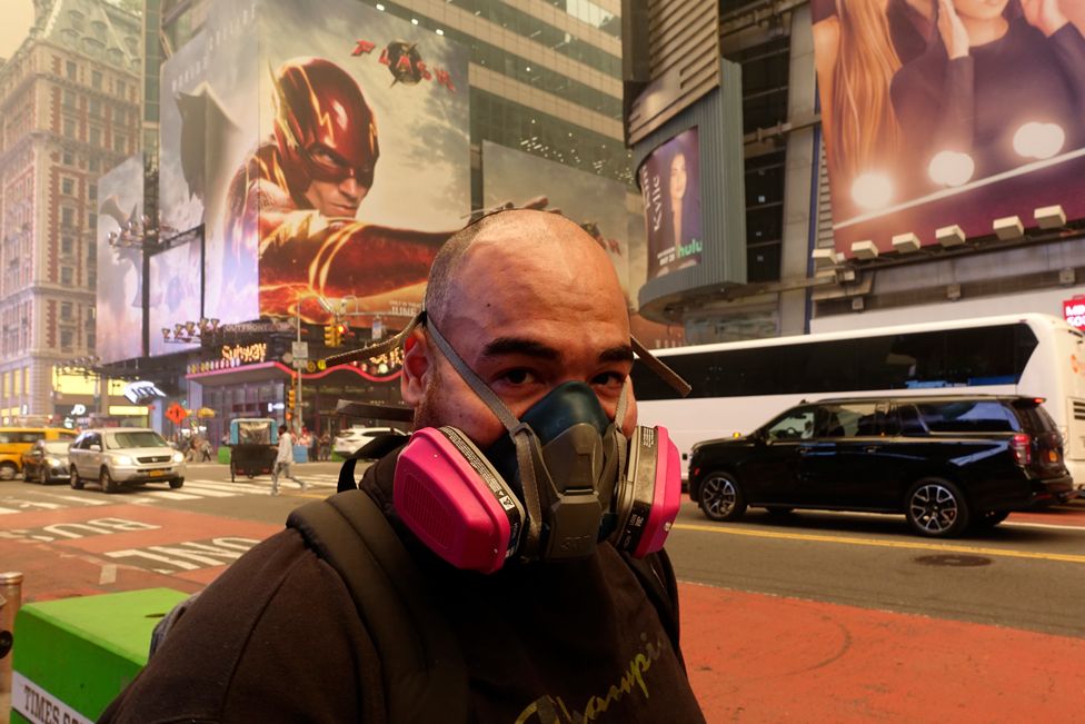 A pedestrian wearing a breathing filter walks in Times Square amid a smoky haze from Canada wildfires on 7 June 2023 in New York City, US