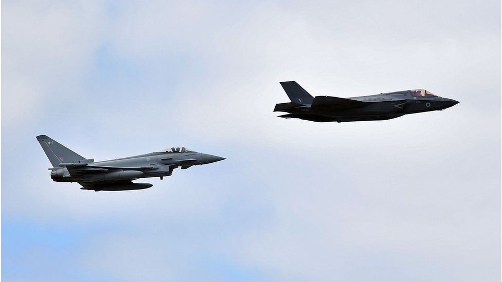 A British Royal Air Force (RAF) Lockheed Martin F-35 Lightning II (R) and a Eurofighter Typhoon aircraft perform a fly-past