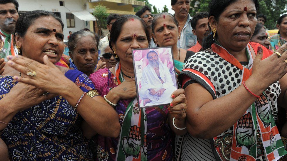 Работники конгресса держат портрет самозваного богочеловека Асарама Бапу, выкрикивая против него лозунги во время акции протеста в районе Амрайвади в Ахмедабаде, 31 августа 2013 г.