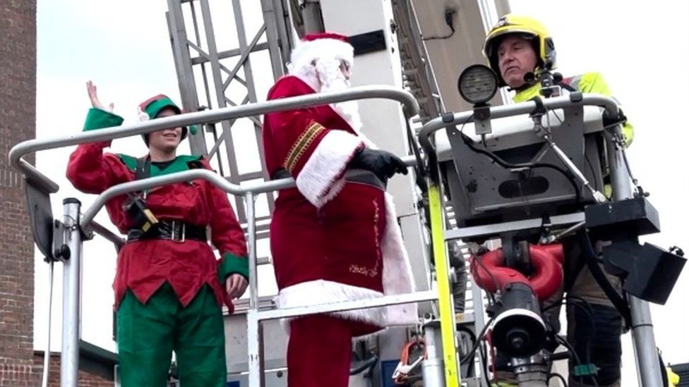 Santa being rescued from the roof by firefighters
