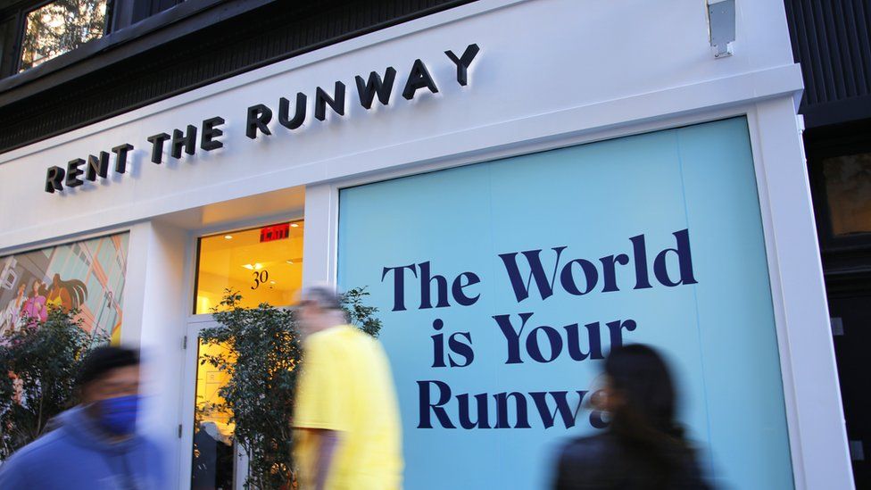 Shoppers walk past a rent the runway store in New York