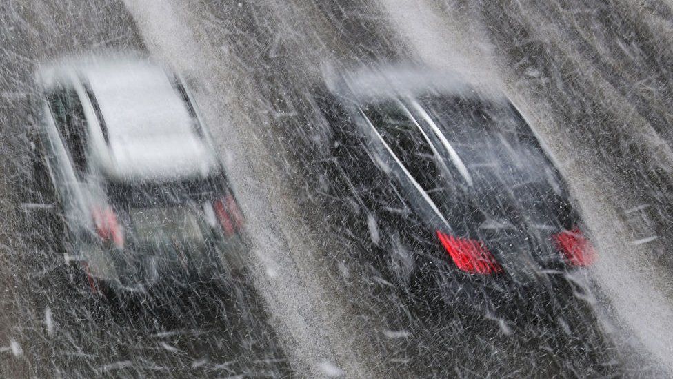 Two cars drive through a fast moving snow storm in America's Midwest