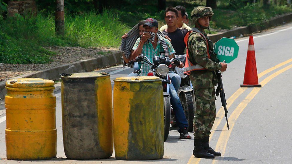 A soldiers stands guard in a streets of Tibu, in the region of Catatumbo, Norte Santander Department, in north-eastern Colombia, talk to a woman and a girl on April 27, 2018.