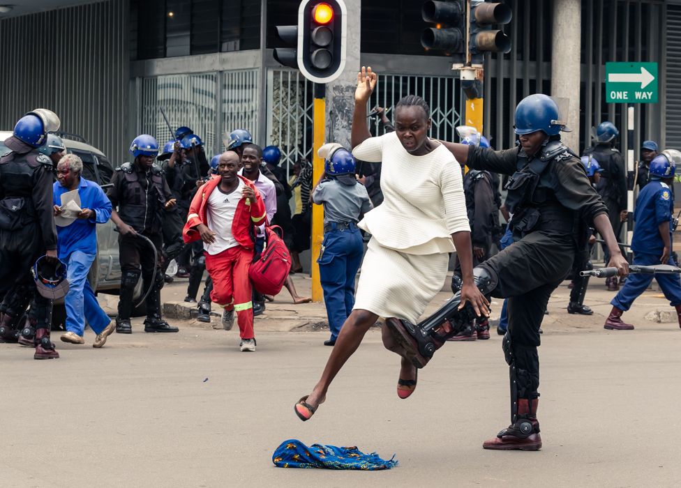 A riot police officer attacks a woman in Harare, Zimbabwe - Wednesday 20 November 2019