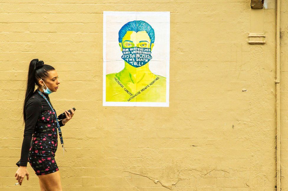 A woman is seen walking past a political poster on March 26, 2020 in Sydney, Australia.
