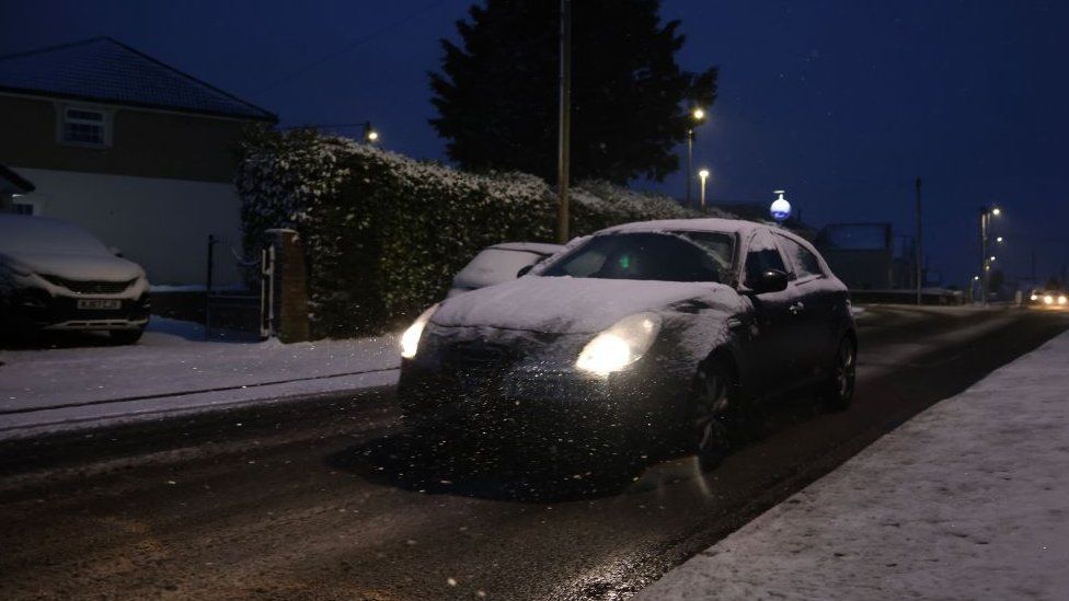 View of a car covered in snow in the dark
