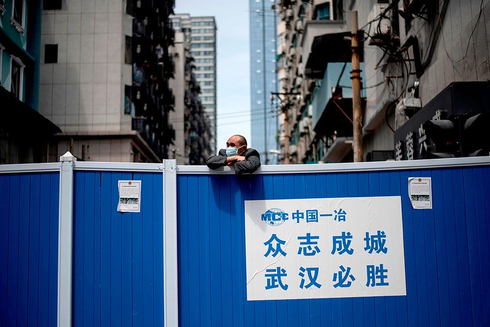 A man wearing a face mask looks over a barricade