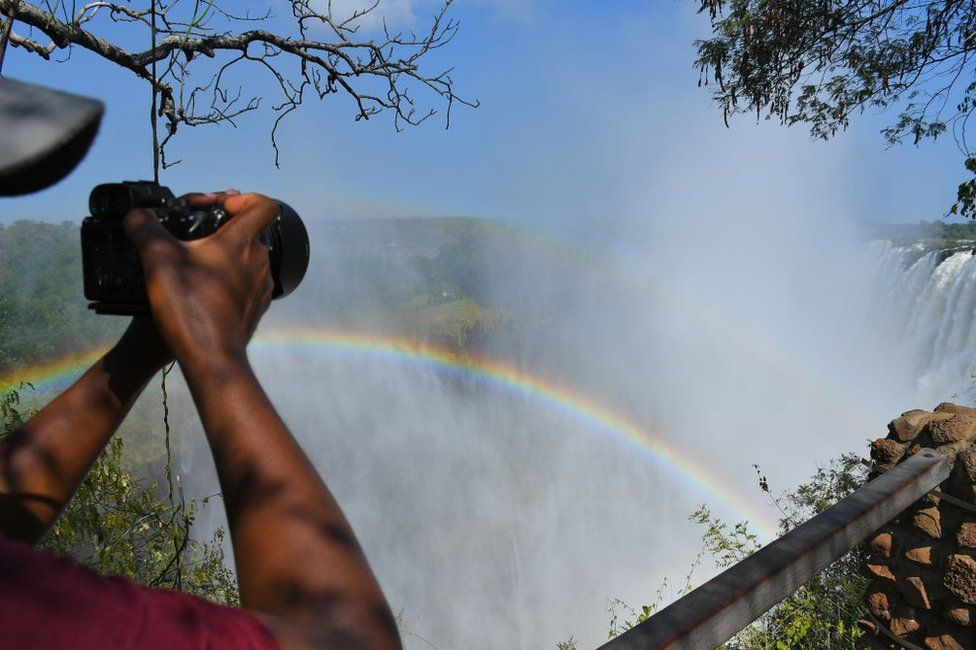 A tourist takes photos of the Victoria waterfall at the border between Zambia and Zimbabwe.